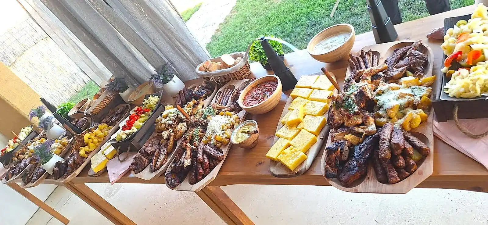 Un bufet vast de carne la grătar diverse, garnituri și aperitive.